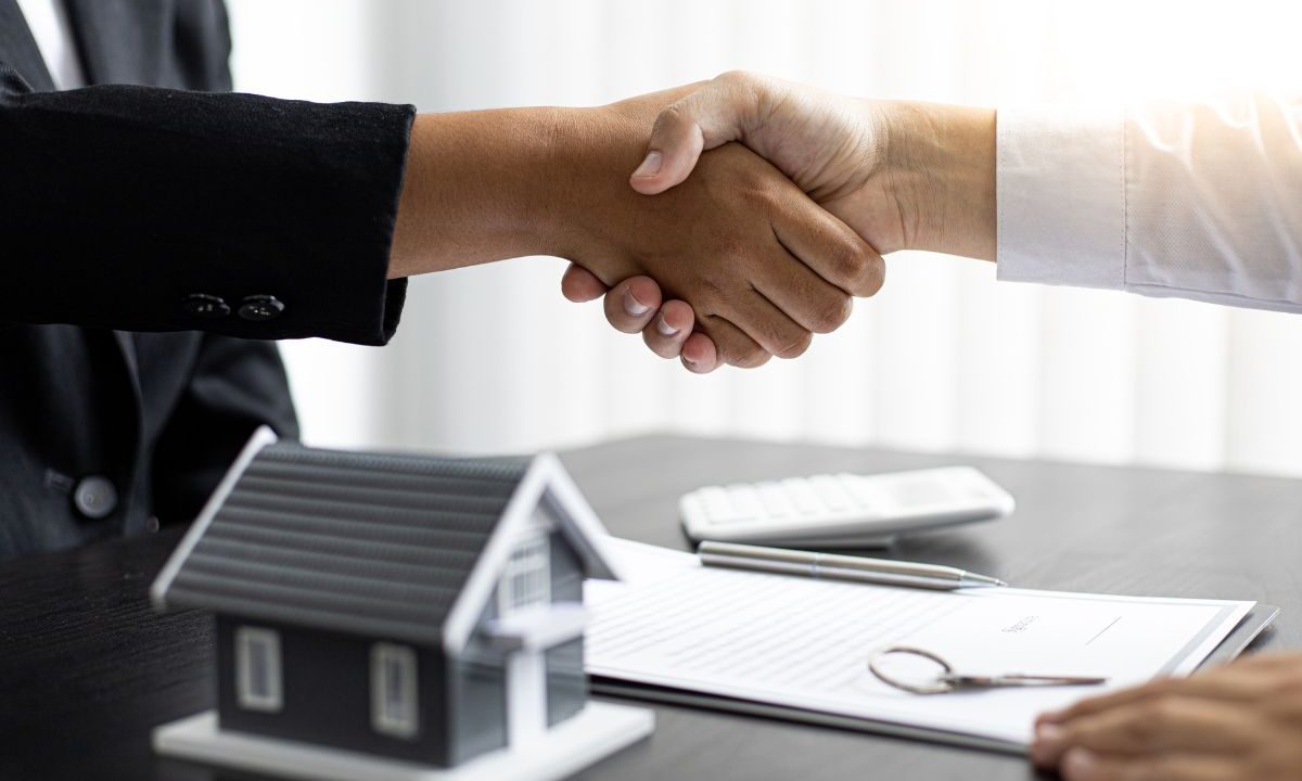 Vendedor y comprador cerrando trato después de vender un piso con hipoteca, dándose la mano